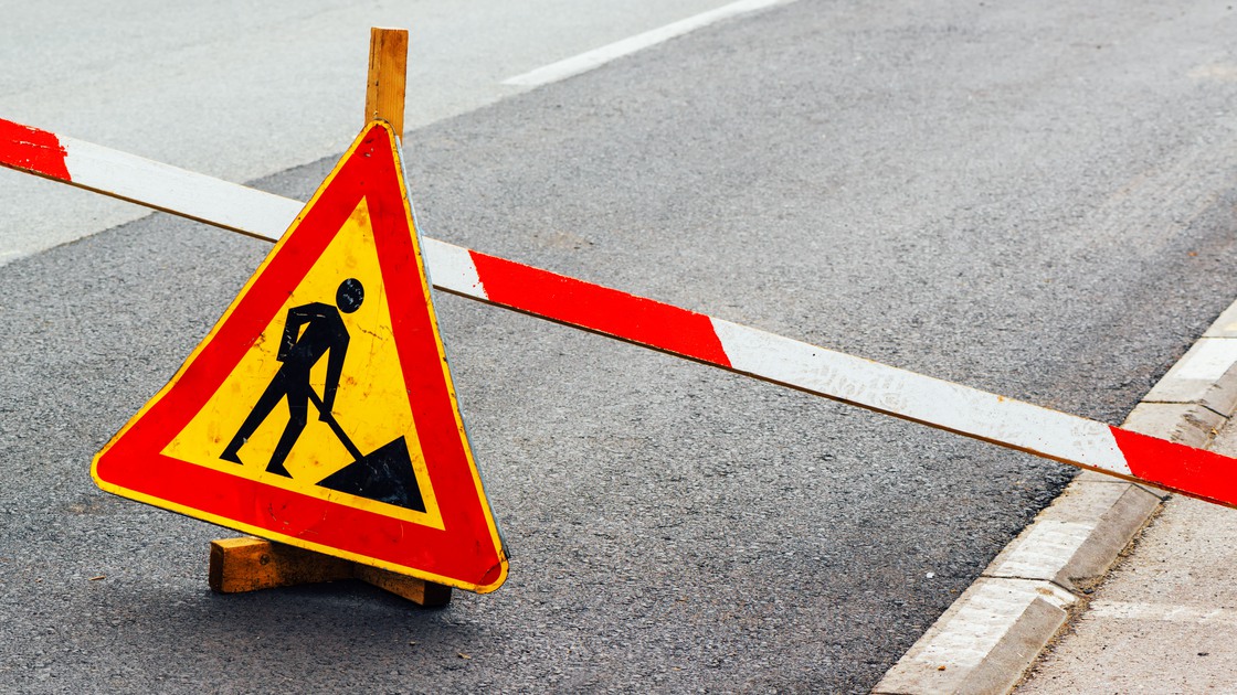 Road construction work sign on asphalt driveway