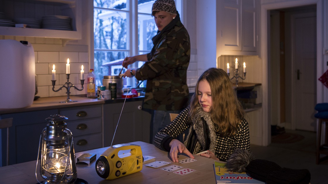 Förälder och barn som lyssnar på radio i ett kök som är strömlöst.