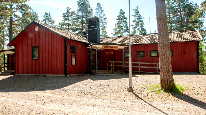 Den röda Rankåsstugan. Talltoppar i bakgrunden.