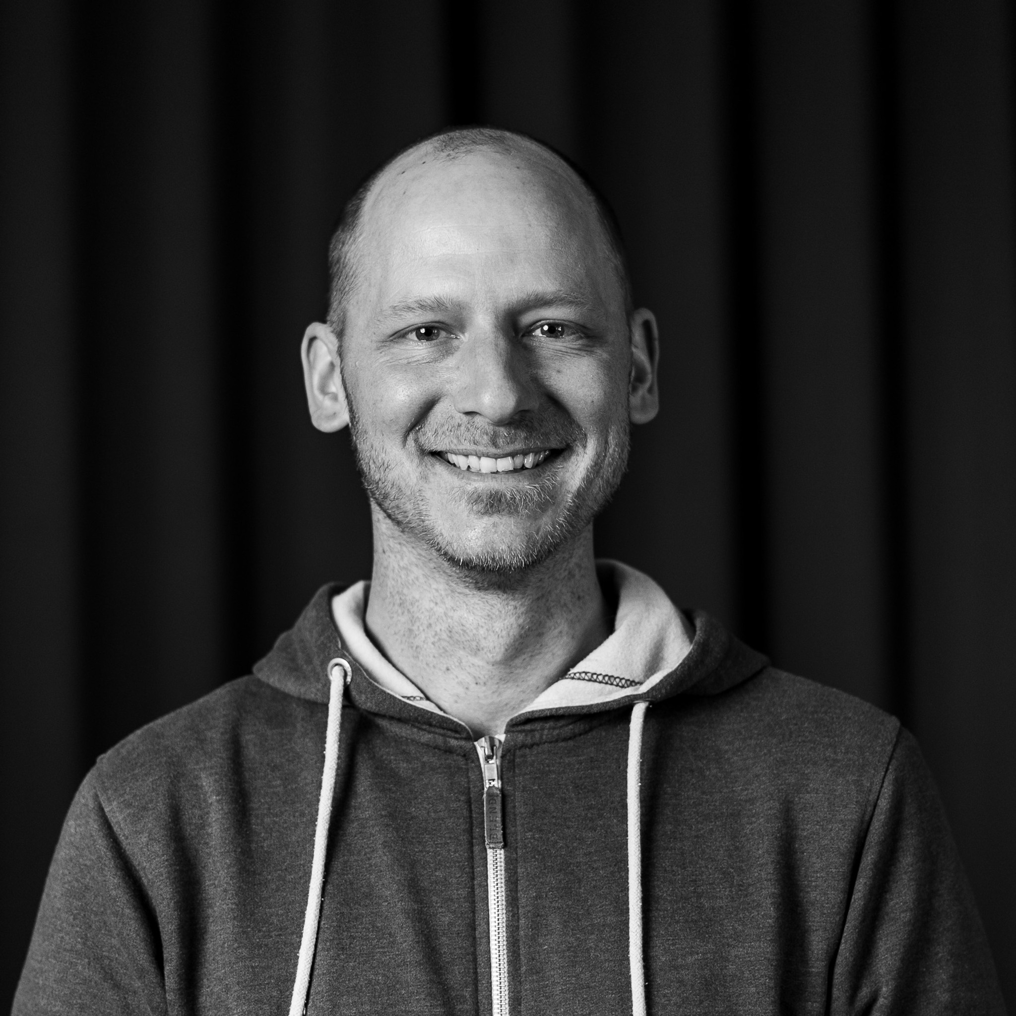 Ett svartvitt foto av en leende man.