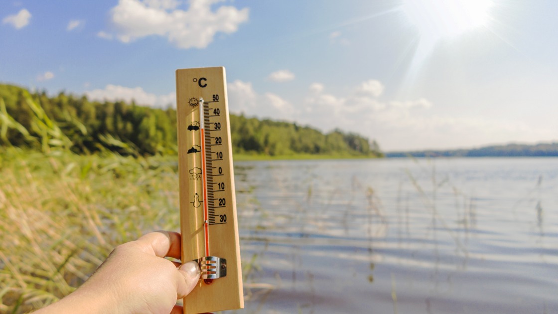 Termometer som visar 30 grader framför en sjö.
