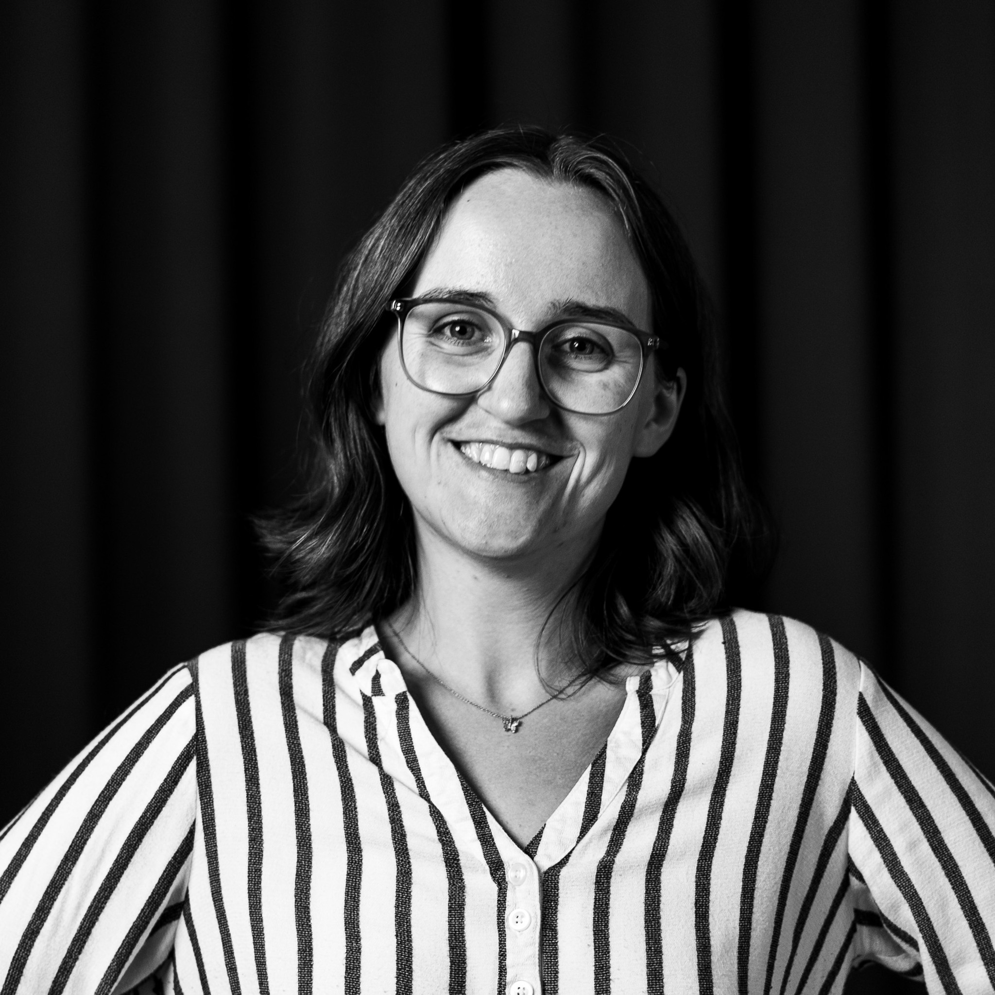 En kvinna med glasögon och randig skjorta.