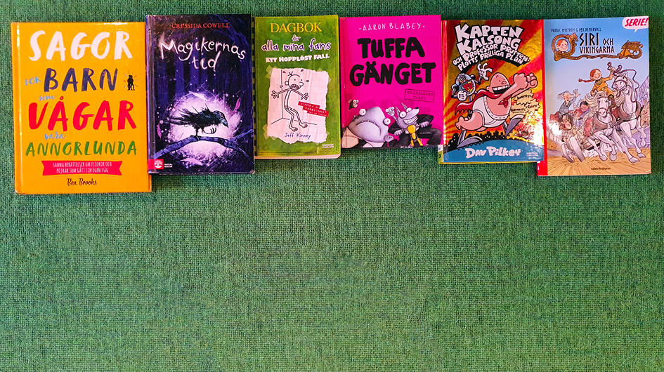 Grön matta. I övre kant sex barnböcker med framsidor i olika storlekar och färger.