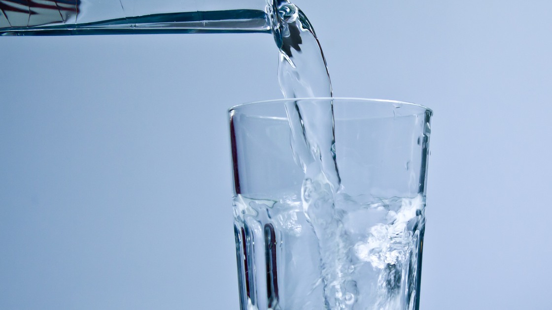 Vatten som rinner ur en kran ned i ett glas.