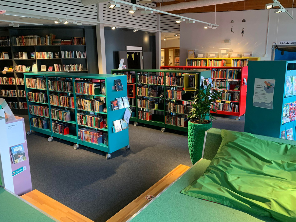Vy över barnavdelningen. Grönt golv i förgrunden. Bokhyllor i olika färger.