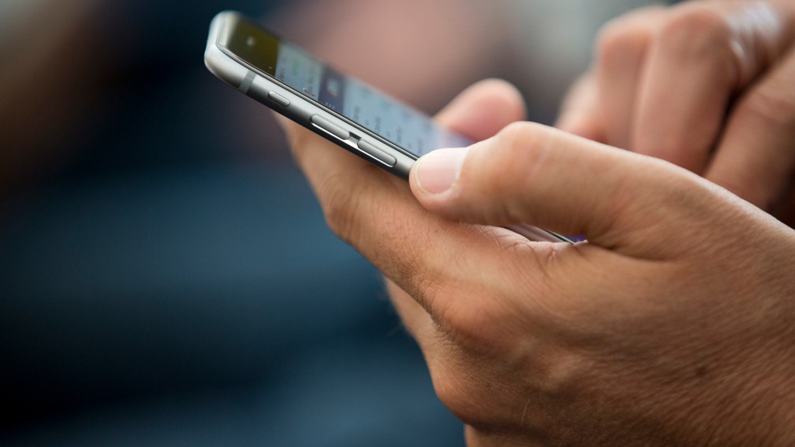 En närbild på en person som håller i en mobiltelefon.