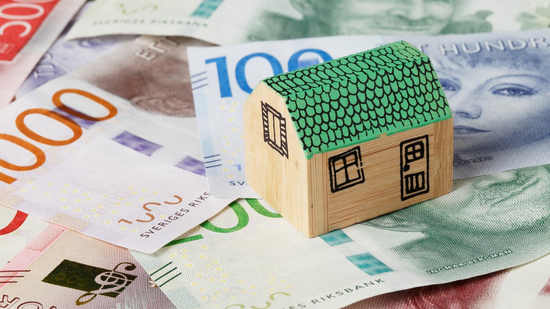 Litet trähus på en bädd av svenska sedlar.