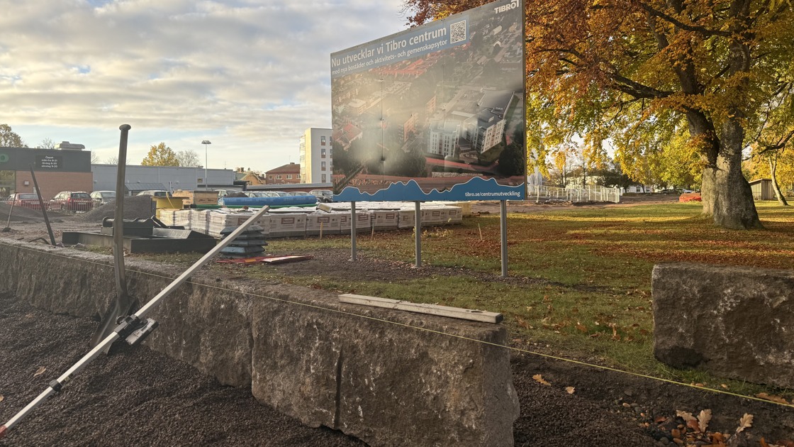 En stenmur byggs framför en skylt med texten Nu utvecklar vi Tibro centrum.