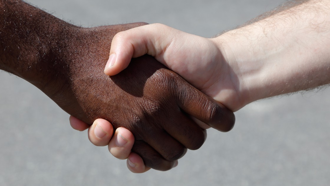 Närbild av en svart och vit mans händer i ett handslag.