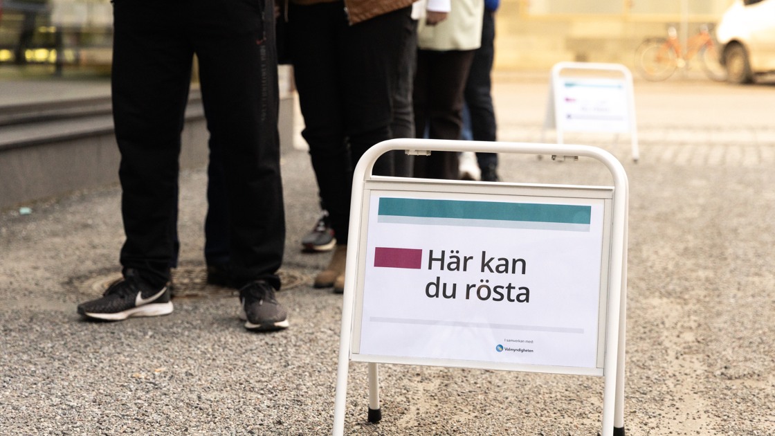 Kö till en vallokal. En skylt där det står Här kan du rösta.